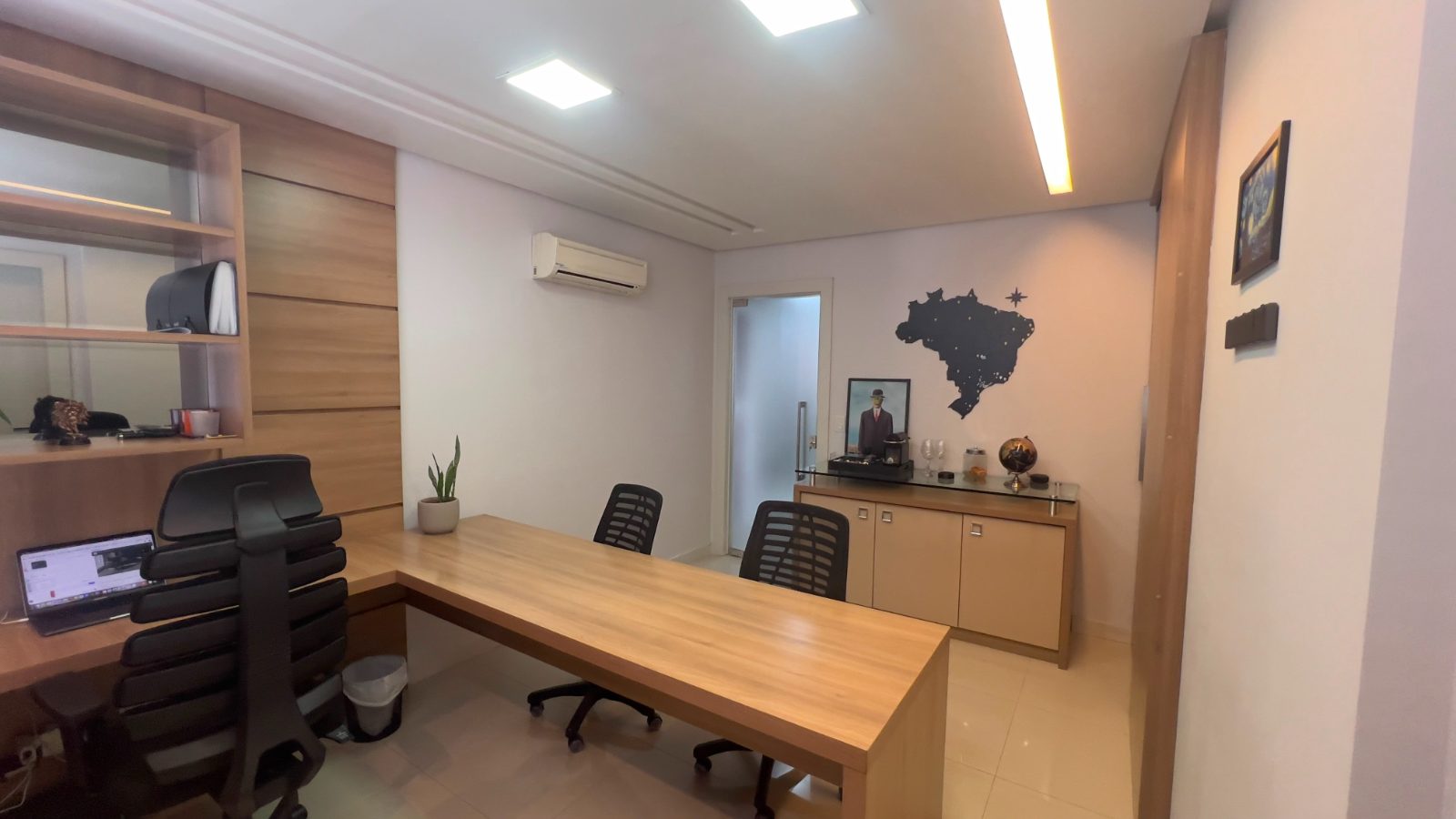 Gabinete de atendimento com mesa em L e mapa do Brasil na parede