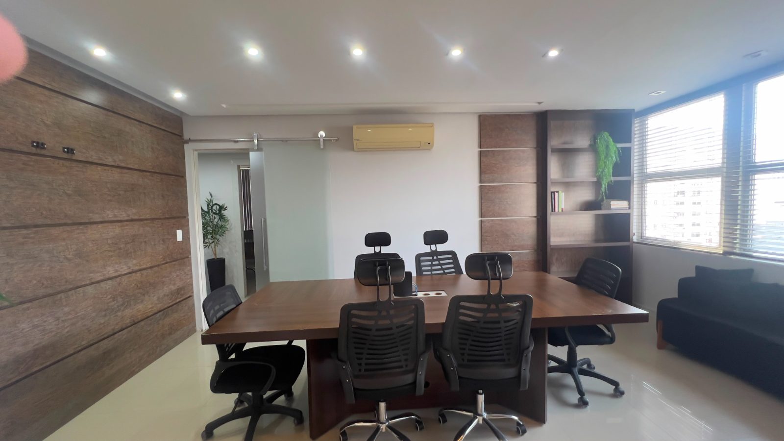 Sala de reunião com mesa de madeira e vista para a cidade